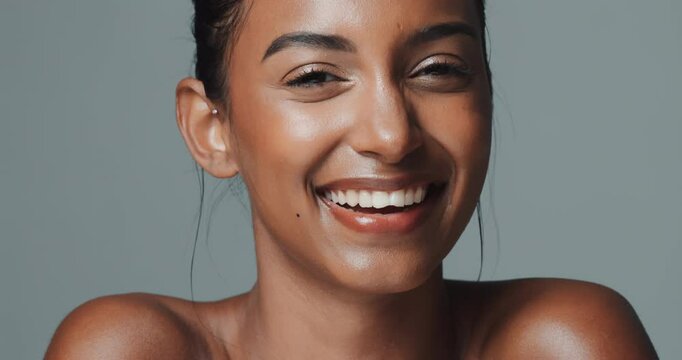 Indian woman, beauty and skincare on studio background with wink and happy face for wellness or confidence. Model, portrait and glow with smile for healthy facial, dermatology and cosmetics or makeup