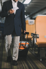 Handsome Asian male passenger takes his carry-on luggage out of the overhead locker after landing at his destination. transportation concept
