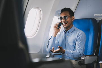 Traveling and technology. happy young businessman working on laptop computer and smartphone while sitting in airplane.