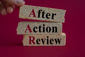 Concept words AAR After action review on brick blocks. Beautiful pink background, businessman hand....