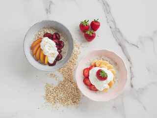 colorful flat lay with breakfast bowls of fresh fruits, yogurt and porridge with whole strawberries on the marble table.