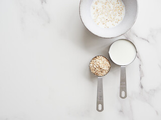 Proportion of ingredients for preparing porridge. Measuring cups with milk and oat flakes. Half a...
