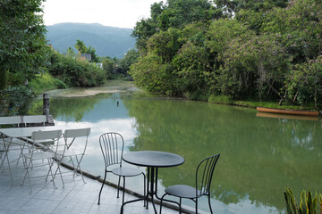 Outdoor dining space area of Restaurant terrace and coffee cafe with natural landscape of green lake view and cloudy blue sky