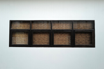 Exterior design and architecture of white building decorated with wooden window frame and bamboo curtain shade 