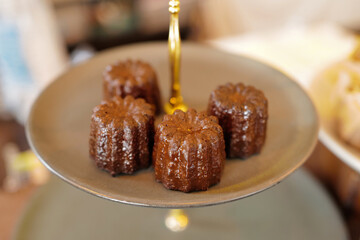 Close up plate of Canelé, small French pastry flavored with rum and vanilla with a soft and tender custard center and a dark, thick caramelized crust