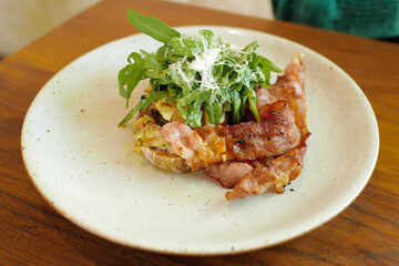 Close up plate of bacon and rocket salad on toast served with sausage