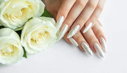 Female Hands on a white background with beautiful pearl manicure and white roses.