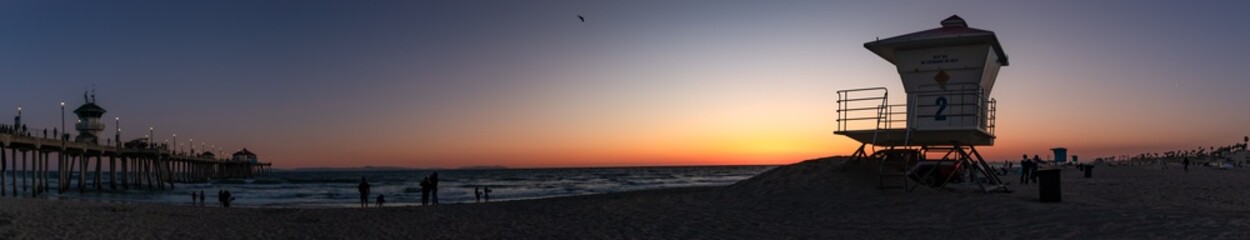 Extra Wide Panorama of Sunset, with Silhouettes of Lifeguard Tower and Distant People, West Side of Pier, April 2024, Huntington Beach, California, USA-distant people