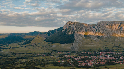 Sun setting over idyllic village with mountains. Meadow. Panoramic view of Rimetea, Transylvania, Romania.