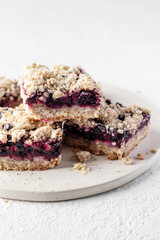 Baked oatmeal bars or crumble squares with fresh blueberry on white background, close up. Menu, recipe