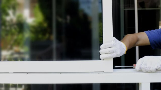 Handyman repairing the sliding window. Adjust a rail wheel and lock hook.
