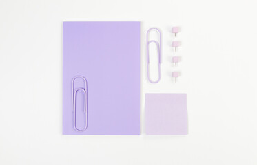 Top view of purple notebook on white background. Purple sticky note, paperclips and pins. School, office wallpaper. Flat lay, copy space.