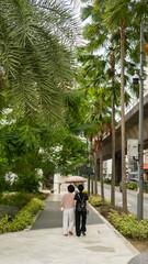 Fototapeta premium two people walking down a sidewalk under palm trees