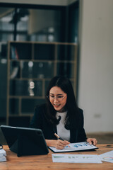 Pretty young Asian businesswoman sitting in office using laptop computer.