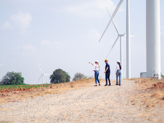 Group of engineers and architects working on the basis of a wind turbine Inspect the structure with the wind turbine in the background.