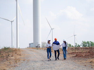 Group of engineers and architects working on the basis of a wind turbine Inspect the structure with the wind turbine in the background.