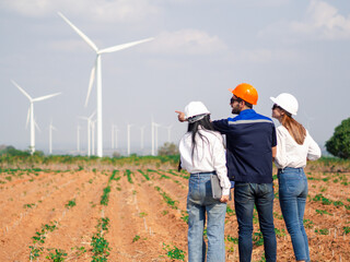 Group of engineers and architects working on the basis of a wind turbine Inspect the structure with the wind turbine in the background.
