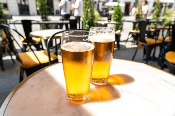 Beer glass in sunny day, cold pint glass with remaining beer on outdoor table, cool condensation