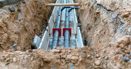Underground pipes being installed in trench. Construction site with visible soil and infrastructure work