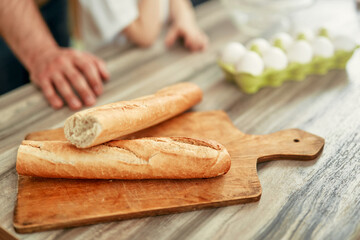 Freshly baked French bread on a wooden cutting board, set in a kitchen atmosphere