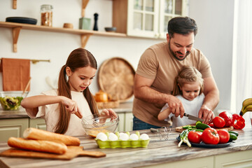 Happy Family Cooking in Kitchen: Father and Children Prepping Vegetables and Baking