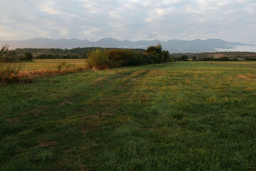 Fototapeta premium Landscape photo with a view of a field and the Carpathian Mountains in the background at dawn near Sibiu, Romania
