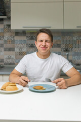 A young man eating in the kitchen.