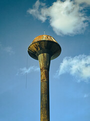 Old rusty water tank tower against blue sky
