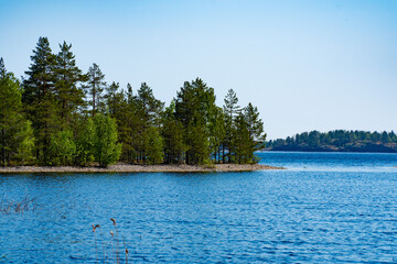 A picturesque forested island surrounded by the pristine blue waters of a tranquil lake. Perfect for nature and travel enthusiasts looking for a serene and natural landscape.