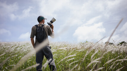 Cameraman standing holding camera in the middle of a meadow
