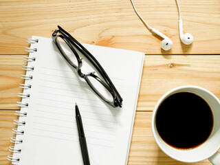 Blank notebook, pen, glasses, black coffee and earphones