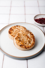Hot Toasted Crumpets with on a plate with strawberry jam nearby. Perfect tasty breakfast