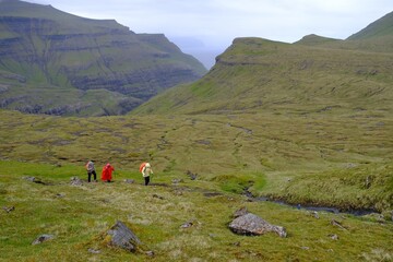 Mountain trip from Saksun village of Saksun to Tjornuvik on island of Streymoy. Silhouettes of hiking people on trail. Faroe Islands, Denmark