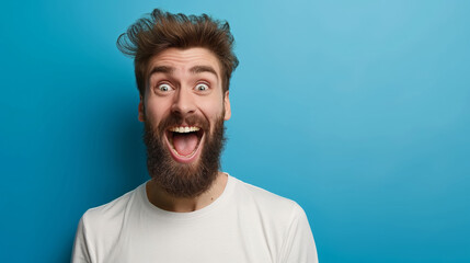 A man with a beard and a white shirt is smiling and laughing. He has a big smile on his face and his eyes are wide open. Concept of happiness and joy