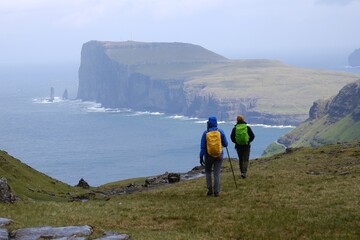 Fototapeta premium Mountain trip from Saksun village of Saksun to Tjornuvik on island of Streymoy. Silhouettes of hiking people on trail. Faroe Islands, Denmark