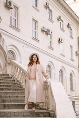 Obraz premium woman in elegant coat and hat against an intricate architectural backdrop, harmoniously blending modern fashion with historical allure. The soft daylight adds to its timeless appeal.