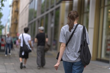 Young woman and other pedestrians on the sidewalk.