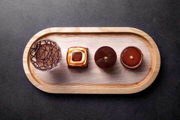 Single Origin Chocolate Flight Toasted Marshmallow Chocolate Tart, cacao Chocolate Puff balls, Chocolate Tart round, with fork served in dish isolated on dark background top view of baked cafe food