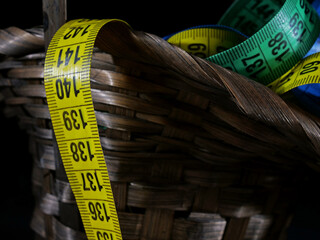 measuring tapes in wicker basket on black background