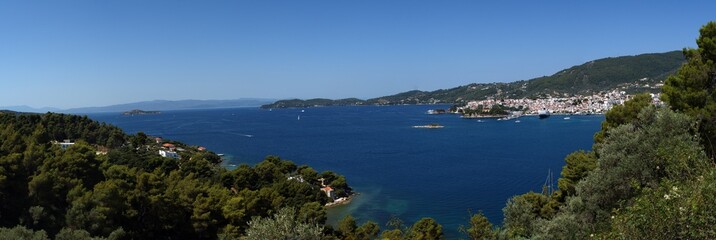 Greek island panorama view, seascape with the blue Aegean waters. Skiathos old town, white washed town houses, holiday, vacation destination. 