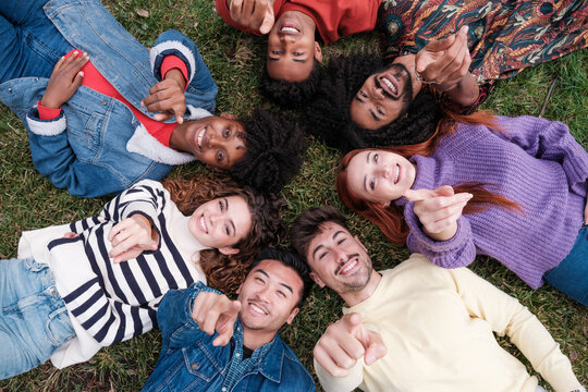 Overhead view of a group of young people pointing the way while lying on the ground. Concept: lifestyle
