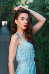 Chic beautiful young woman model with red lips in a fashion vintage dress walks in the park