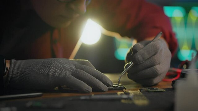To correct. An engineer uses professional skills to repair a phone in an electronics laboratory. A working Caucasian man takes out a chip board and introduces innovative repair methods, laboratory