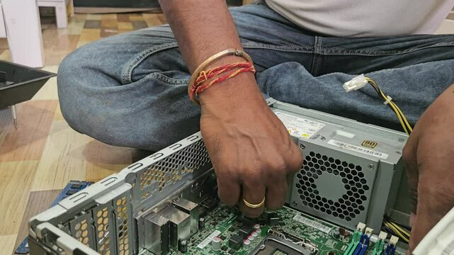 A man is repairing a desktop computer. The concept of computer repair. Close up of unidetified man repair computer motherboard with a screwdriver. Maintenance of the hardware of the motherboard.