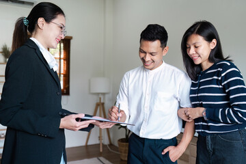 Real Estate Agent Showing Documents to Happy Clients in Modern Home Interior