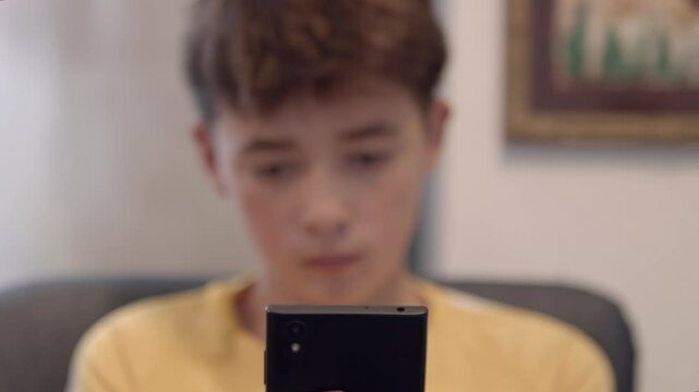 Adolescente viendo el m&oacute;vil cambio de foco de el a m&oacute;vil y m&oacute;vil a el.