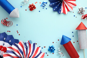 Obraz premium Patriotic red, white, and blue paper fans, fireworks rockets, party streamers on light blue background. US Independence Day 4h of July celebration concept.