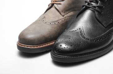 Two different men's brogue boots on a white background