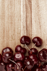 a large ripe cherry in drops of water lies on a wooden board