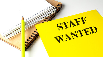 STAFF WANTED text on yellow paper with notebooks